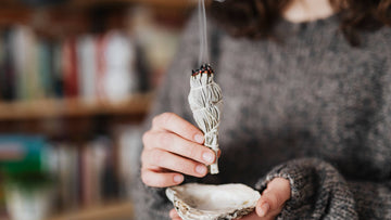 A woman burning White Sage at home