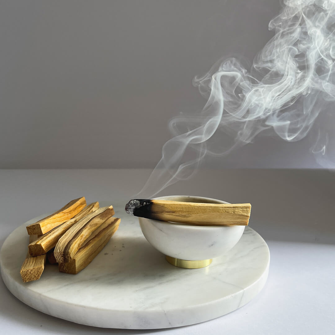 A burning Palo Santo Stick on an incense burner