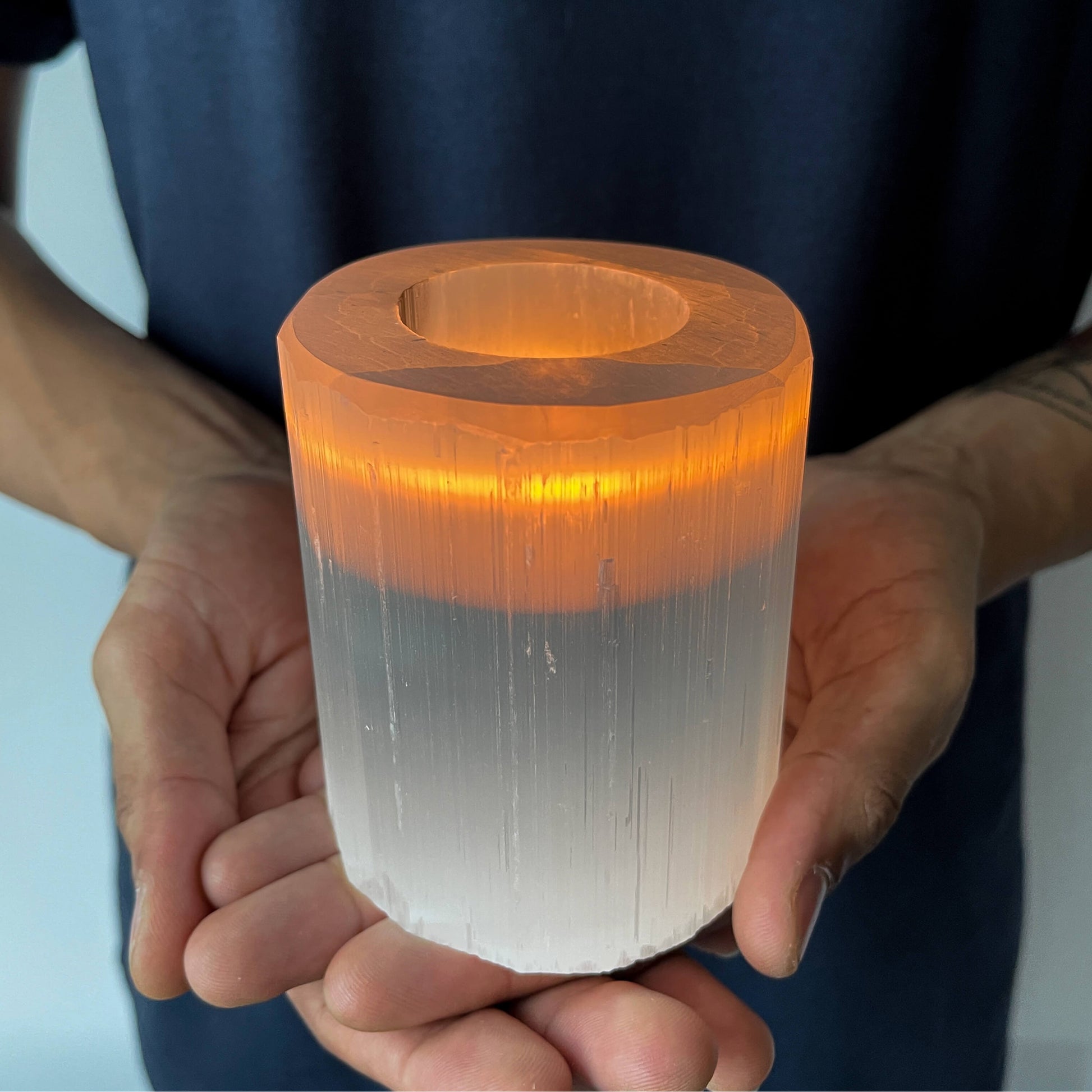 A lighted candle inside a Selenite Crystal Candle Holder